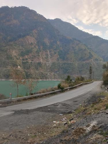 an empty road next to a mountain with a lake at Chamera Inn Homestay in Chamba