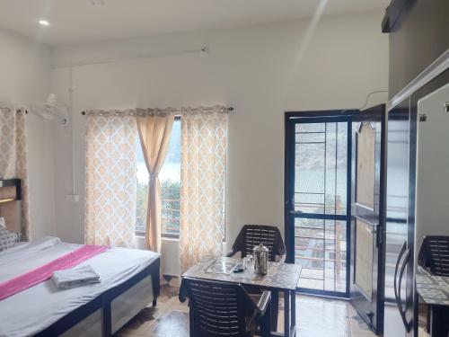 a bedroom with a bed and a table and a window at Chamera Inn Homestay in Chamba