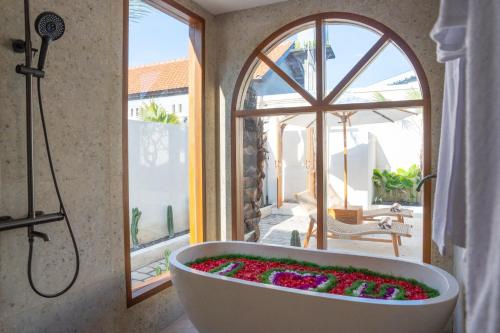 a bath tub filled with flowers in a bathroom with a window at Dianatara Villa by Dhananjaya Hospitality in Sukawati