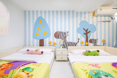 Dos camas en una habitación infantil con un mural de un árbol en 青岛旺莎主题民宿, en Qingdao