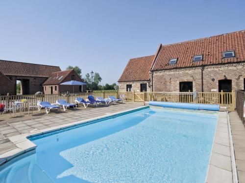 a swimming pool with blue chairs and a building at Pantiles Barn - E3866 in Runcton Holme