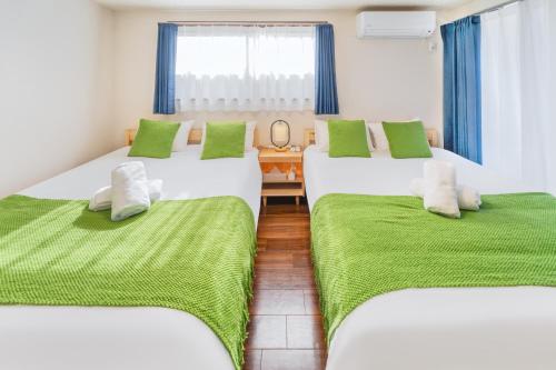a room with three beds with green sheets and a window at 202 Room, a 6-minute walk from Tokyo Koiwa Station Direct connected to Shinjuku and Akihabara Stations Comfortable one-bedroom apartment with separate wet and dry areas in Tokyo