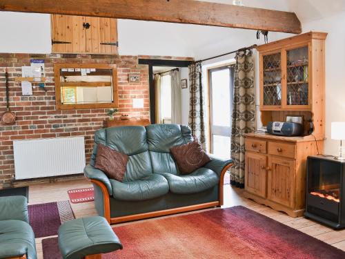 a living room with a leather chair and a fireplace at High House Holiday Cottages 1 in Hooe
