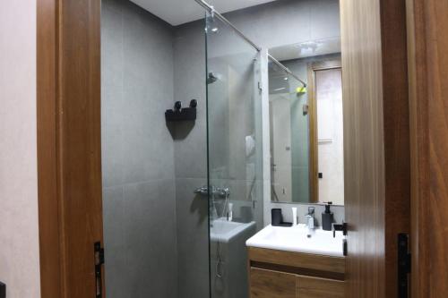 达布阿扎Dar Bouazza Luxury apartment with pools garden sports courts parking near the sea的浴室里有淋浴、洗手池和镜子。