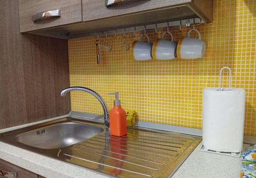 a kitchen sink with a faucet and cups on the wall at Sicilia Bedda Casa Vacanze in Lascari