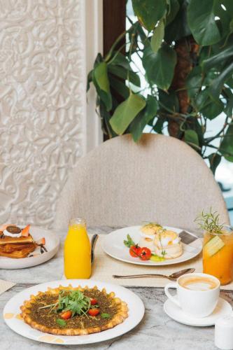 a table topped with plates of food and orange juice at JW Marriott Marquis City Center Doha in Doha