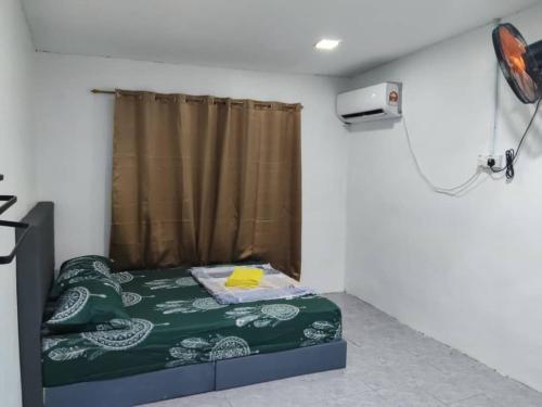 Un dormitorio con una cama con un edredón verde. en Qmar D Sepang, en Sepang