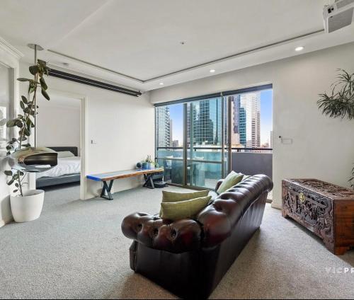 un soggiorno con un divano in pelle e una grande finestra di Penthouse Retreat in Heart ofCBD a Melbourne