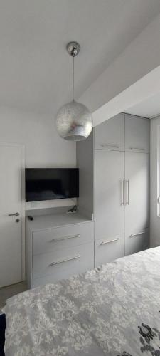 Dormitorio blanco con cama y lámpara colgante en Apartman Vaske 2, en Brčko