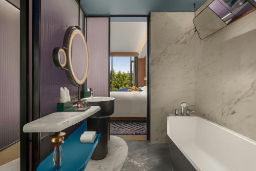een badkamer met een bad en een wastafel en een ligbad bij Renaissance Hangzhou Lin'an Hotel in Hangzhou