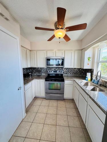 a kitchen with white cabinets and a ceiling fan at North Shore Duplex #54588 Duplex in Anna Maria
