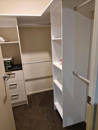 un dressing avec des armoires blanches et une porte dans l'établissement Master bedroom, à Tauranga
