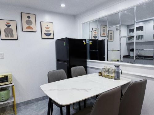 eine Küche mit einem weißen Tisch und einem schwarzen Kühlschrank in der Unterkunft Kem Homestay 2 - Nhà riêng 2 phòng ngủ in Haiphong