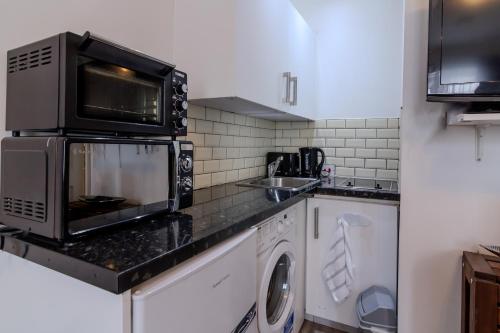 ブロムリーにあるCosy Studio Flatの電子レンジ、洗濯機、乾燥機付きのキッチン