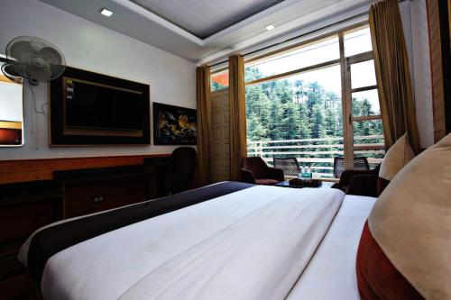 a bedroom with a large bed and a television at Staynest BNB - Balcony Rooms - 3BHK Apartments in Shimla