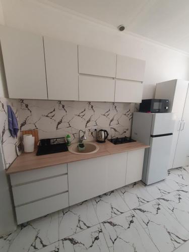 Una cocina blanca con fregadero y refrigerador. en House Hakobyans, en Gyumri