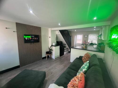a living room with a green couch and a kitchen at Mint Cottage - pet friendly house in Kendal in Kendal