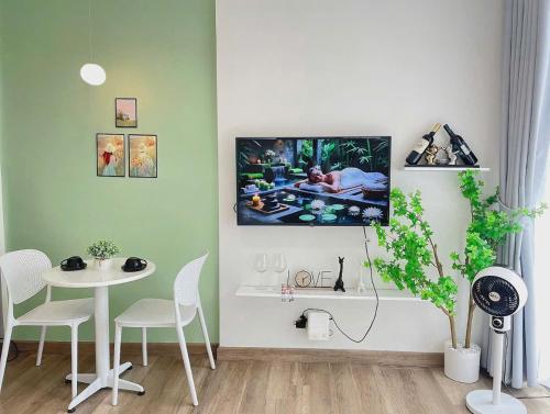 a living room with a table and a tv on the wall at Ecopark Homestay - Căn hộ studio, 1 ngủ, 2 ngủ, 3 ngủ - Bể bơi, phòng gym, tắm khoáng Onsen in Kim Quan