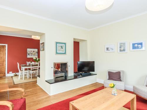 a living room with a fireplace and a table at Lapwing in Yarmouth