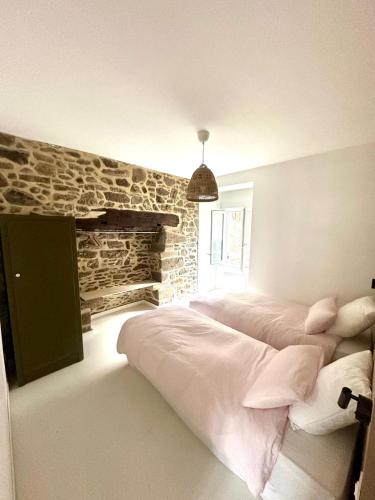 a bedroom with a bed and a stone wall at Appartement au port de Dinan Belle île in Dinan