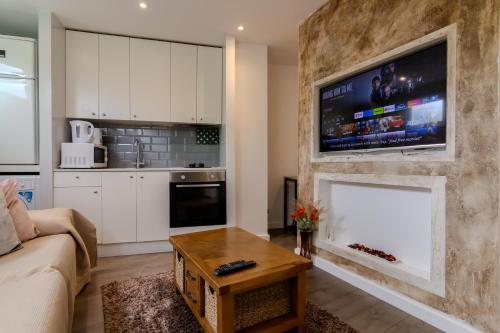a living room with a fireplace with a flat screen tv at Modern Studio Apartment with Free Wifi in Bromley