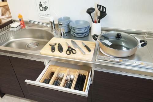 a kitchen counter with a sink and a counter top with utensils at YUFU-Inn プライベートな露天風呂付き-由布院駅徒歩2分 in Yufuin