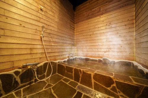 a sauna with a stone tub in a wooden wall at 由布の宿 YUFU-Inn 藤 松 プライベートな露天風呂付き-由布院駅徒歩2分 in Yufu