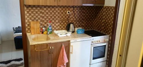 Una pequeña cocina con fregadero y estufa. en shared rooms, en Pristina