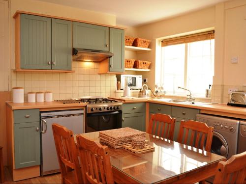 a kitchen with green cabinets and a table with chairs at Valentine Cottage in Keswick
