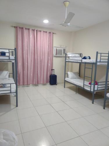 a dorm room with bunk beds and a tiled floor at Muscat Galaxy Hostel in Muscat
