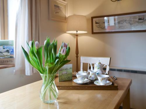 a vase of tulips sitting on a table with a vase of tea at Hadrians Garden Villa in Bardon Mill