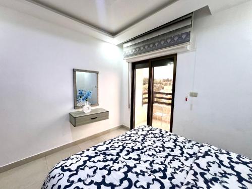 a white bedroom with a bed and a mirror at Ammon Sun Residence in Amman