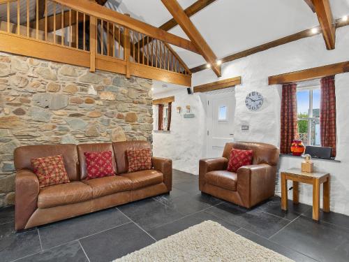 ein Wohnzimmer mit 2 Sofas und einer Steinmauer in der Unterkunft Temple Cottage in Abercastle