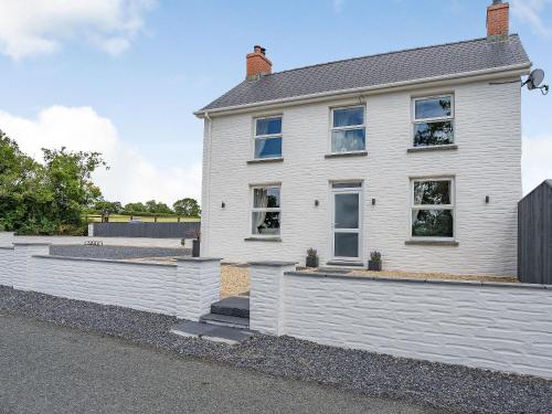 a white house with a fence in front of it at Penlon Cwrws in Llangynllo