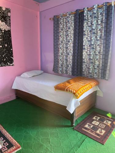 a small bedroom with a bed and a window at Munsiyari ECO homestay in Munsyari