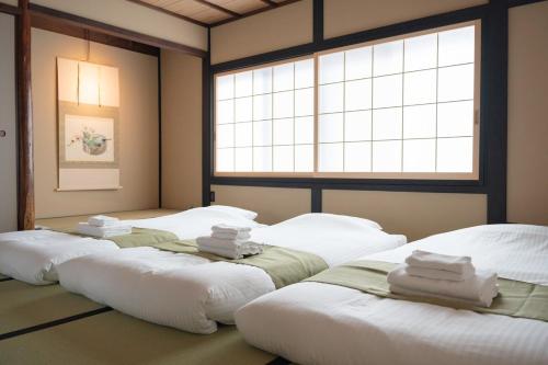two large beds in a room with a window at Authentic Kyoto Machiya Sleeps 7 Near Station in Fushimi