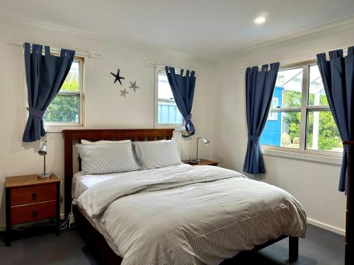a bedroom with a large bed with blue curtains at Dunes Blue at Robe in Robe