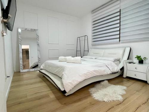 Un dormitorio blanco con una cama grande y un espejo. en הבית בחוף הזהב, en Cesarea