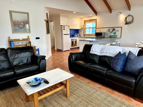 a living room with a black leather couch and a table at Dunes Blue at Robe in Robe