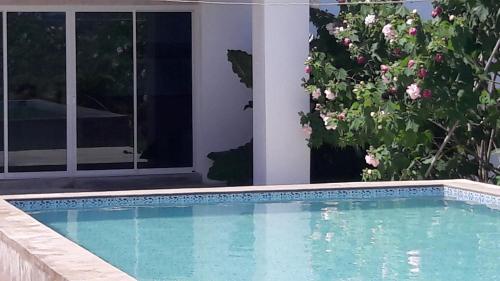 a swimming pool in front of a house with flowers at Bahn Nuan
