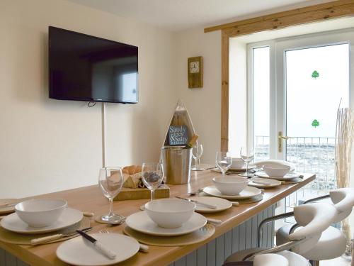 Una mesa con platos y vasos blancos y un televisor. en Making Waves, en Anstruther
