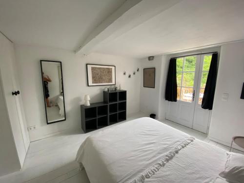 a white bedroom with a bed and a window at la cachette bas in Salies-de-Béarn