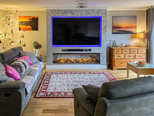 a living room with a large tv and a fireplace at Rivendell Lodge - Cottage in East Winch