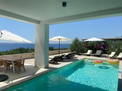 einen Pool mit einem Tisch, Stühlen und einem Sonnenschirm in der Unterkunft Villa Rocky Beach in Ražanac