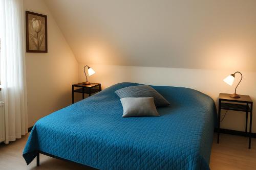 a bedroom with a blue bed with two lamps at Strandhuset i Øster Hurup in Øster Hurup