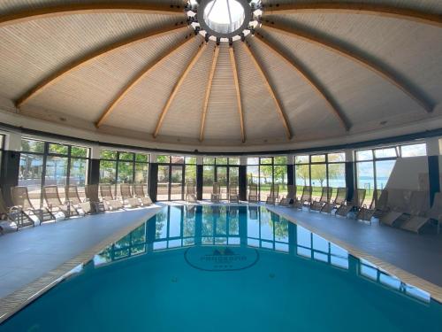 an indoor pool with chairs and a large ceiling at Premium Hotel Panoráma in Siófok