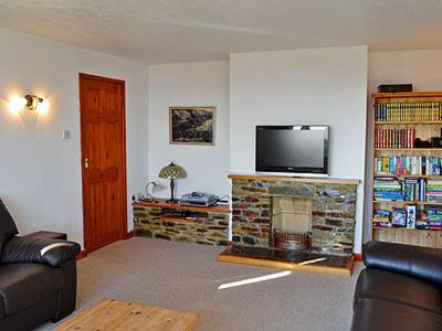 a living room with a couch and a fireplace with a tv at Ponsgwedhen in Coverack