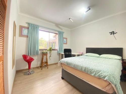 a bedroom with a bed and a desk and a window at Tranquil Garden Constantiaberg in Sweet Valley