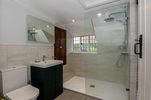 ein Badezimmer mit Dusche, Toilette und Waschbecken in der Unterkunft Beautiful 5-Bedroom Home with Cinema & Games Room 