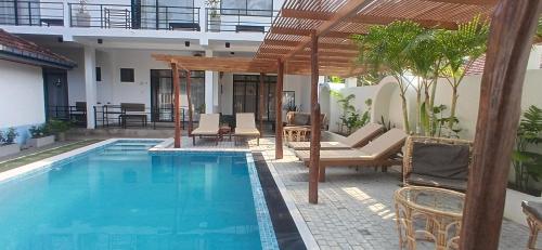 a swimming pool with chairs and a pergola at SriMany in Mirissa